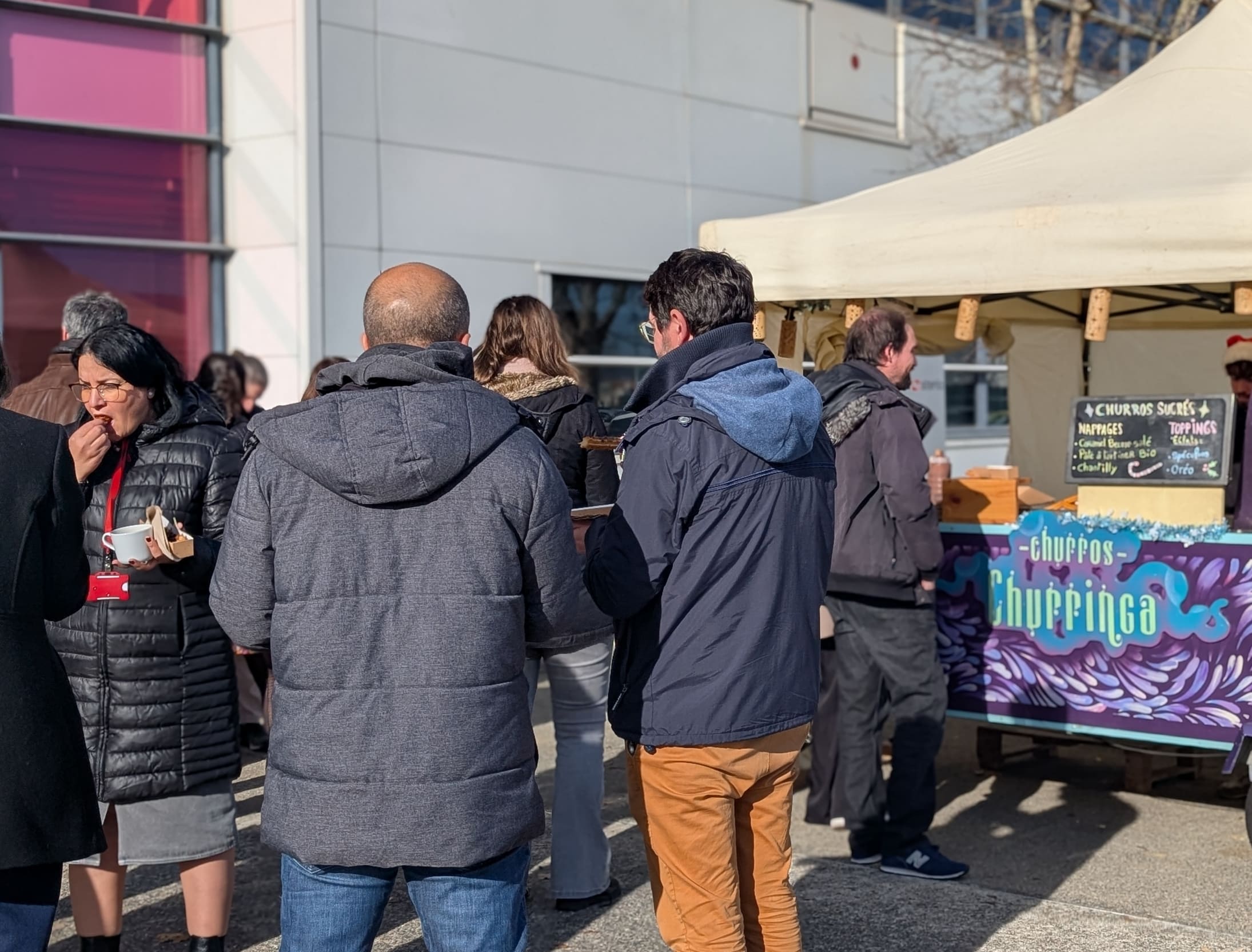 Moment de dégustation au stand de churros Churringa : une cliente savoure ses churros artisanaux lors d'un événement d'entreprise en extérieur par temps ensoleillé